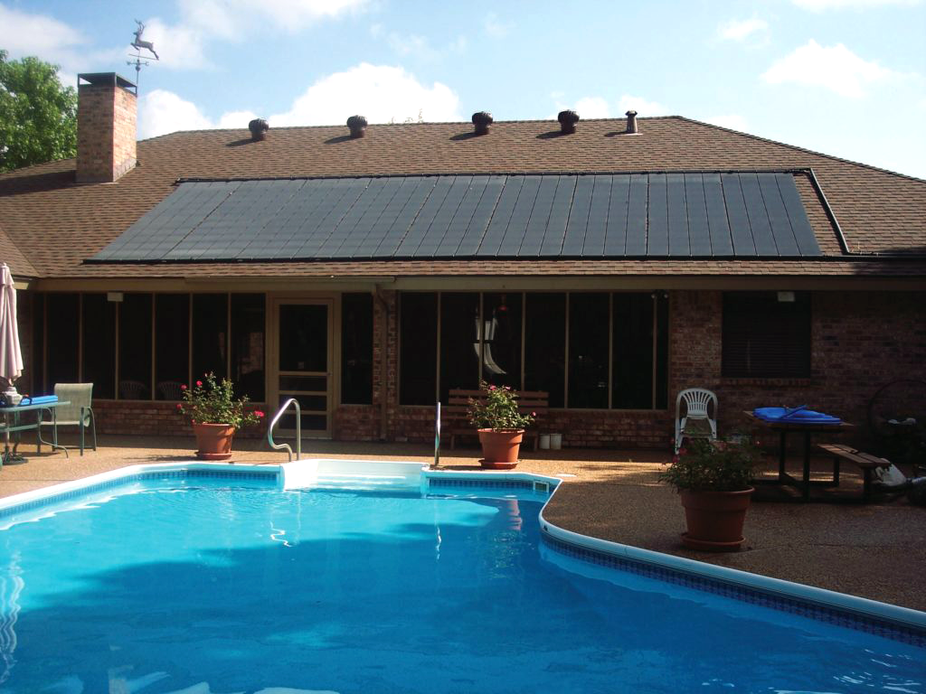 Residential house with solar panels on the roof, set in a backyard featuring a clear blue swimming pool and patio area with chairs and potted plants.