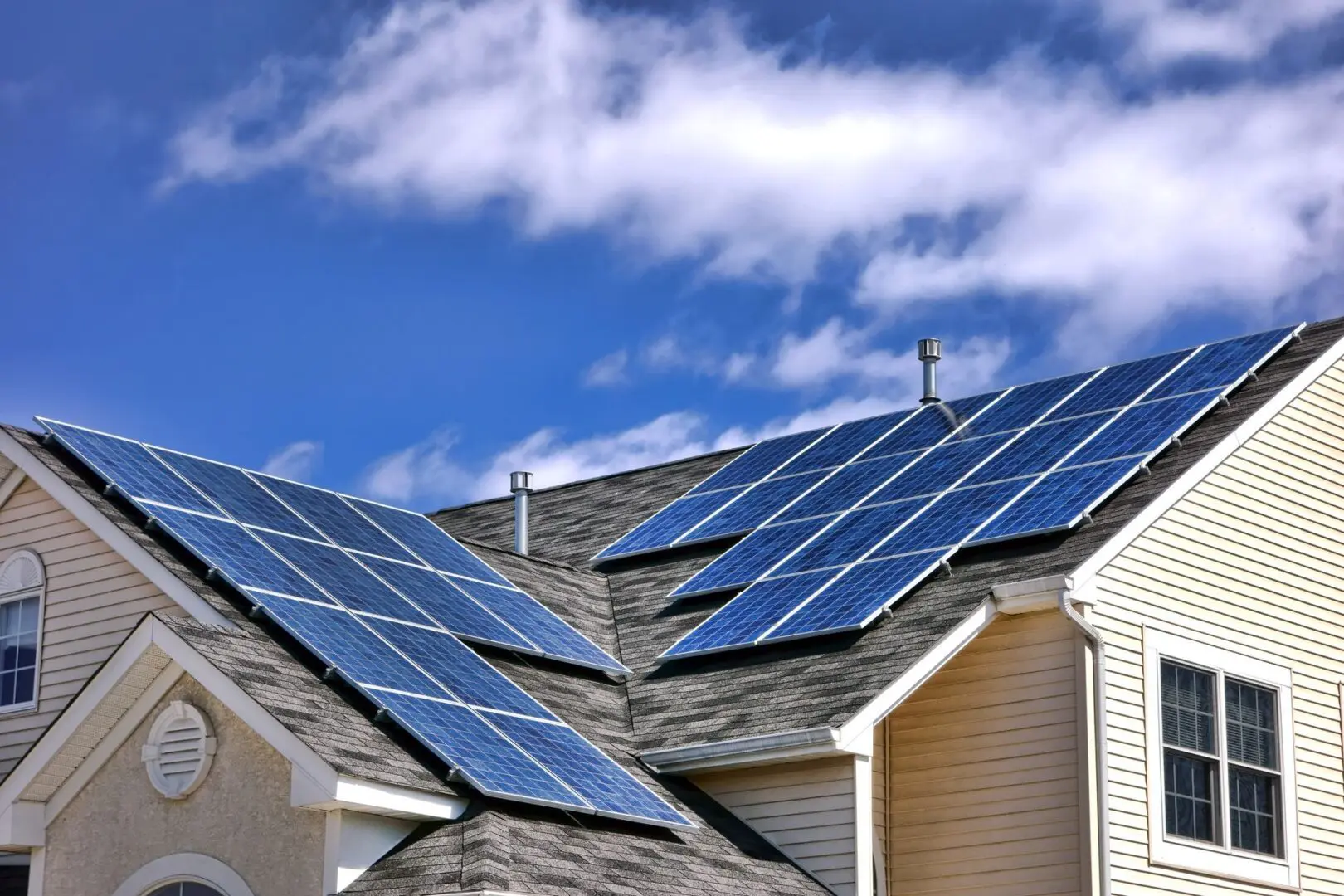 A house with solar panels installed on its roof under a partly cloudy sky.