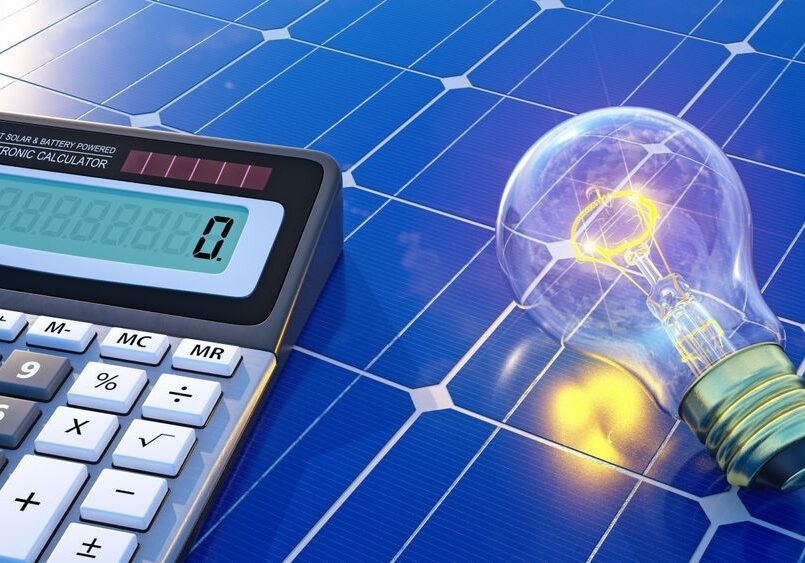 A solar-powered calculator displays zero next to a light bulb resting on a solar panel.