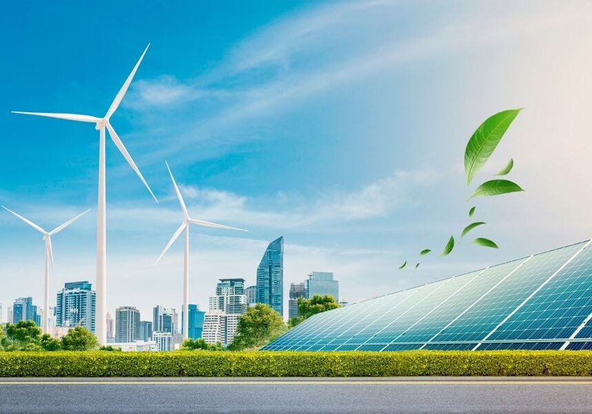 Wind turbines, solar panels, and green leaves in front of a city skyline under a clear blue sky.